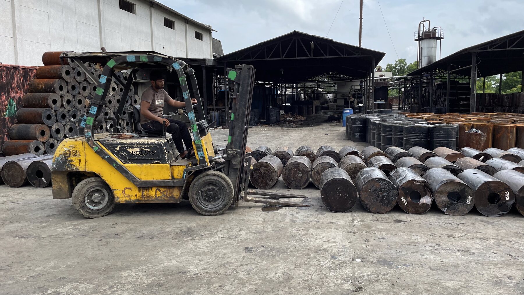 Forklift moving industrial drums inside the factory yard